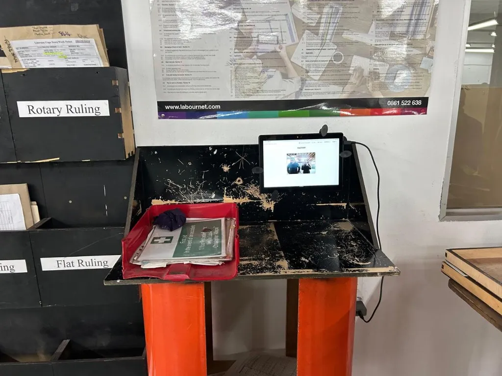 CrewPulse kiosk app on a tablet mounted at a factory desk workstation